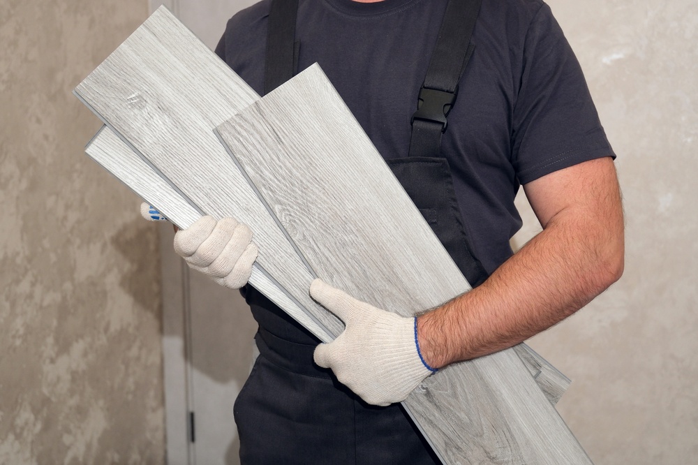 Instalador sosteniendo pisos laminados y vinílicos con acabado tipo madera.